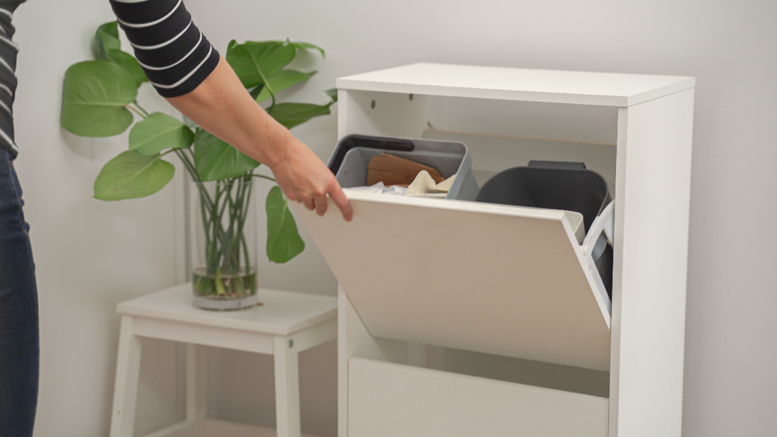 Nainen avaa kenk&auml;kaappia, jossa lajiteltuja roskia.