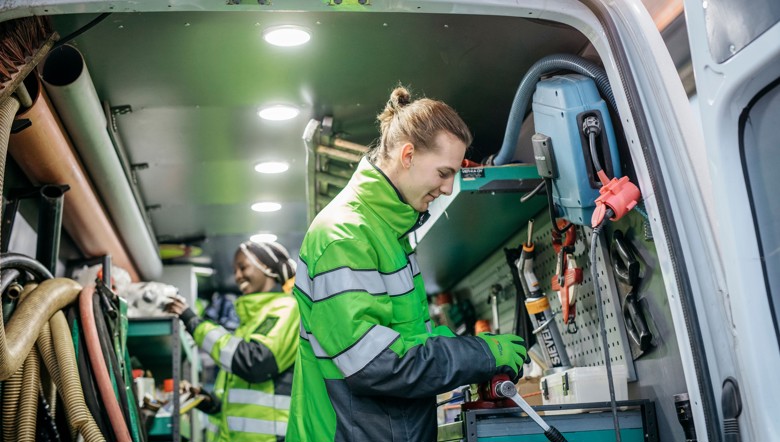 Työntekijöitä pakettiautossa. Autossa näkyy putkiasentajan työkaluja. 