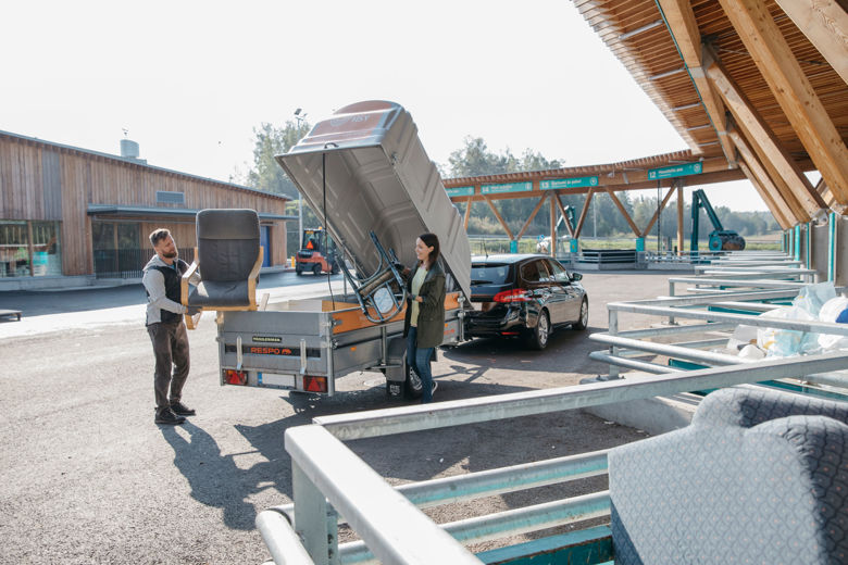 A man and a woman lifting two chairs at a Sortti Station.