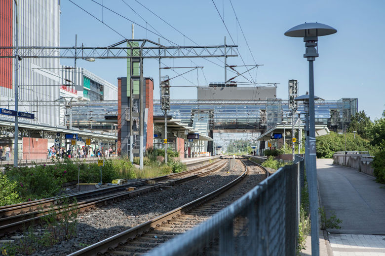 A railway station and a crowd in its platform. A shopping mall in the background.